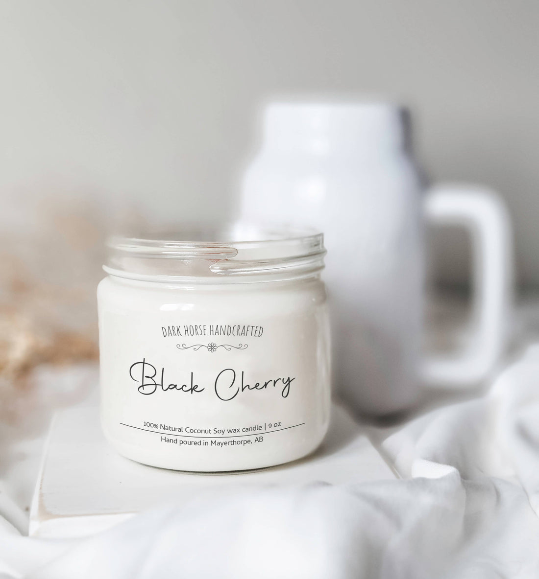 Black Cherry soy candle with black lid beside white blooms in a mason jar