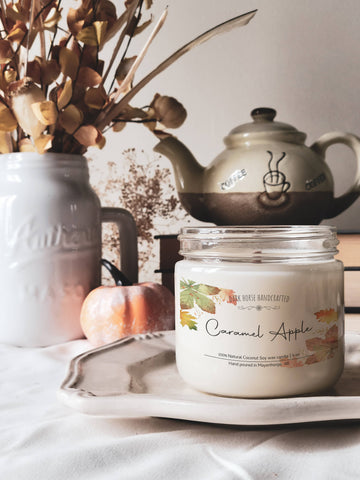 Caramel Apple soy candle in a glass jar styled with a teapot and mini pumpkin