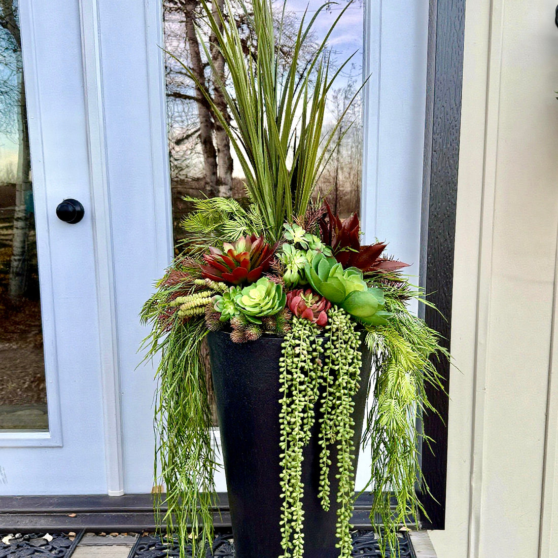 Decorative plant arrangement in a black pot on a porch
