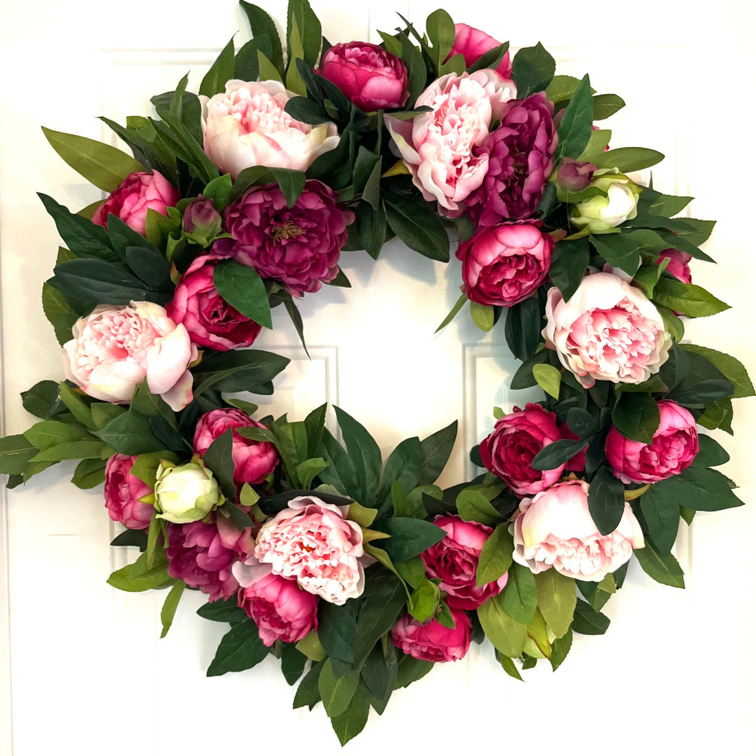 Floral wreath with pink and purple flowers on a white door