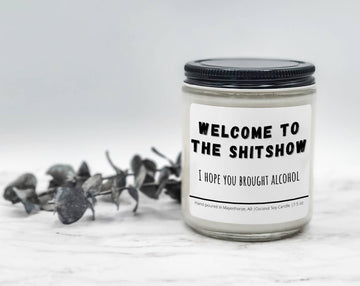 Welcome to the Shitshow novelty candle jar with a black lid and eucalyptus stem