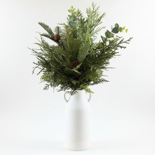 White vase with greenery on a wooden floor
