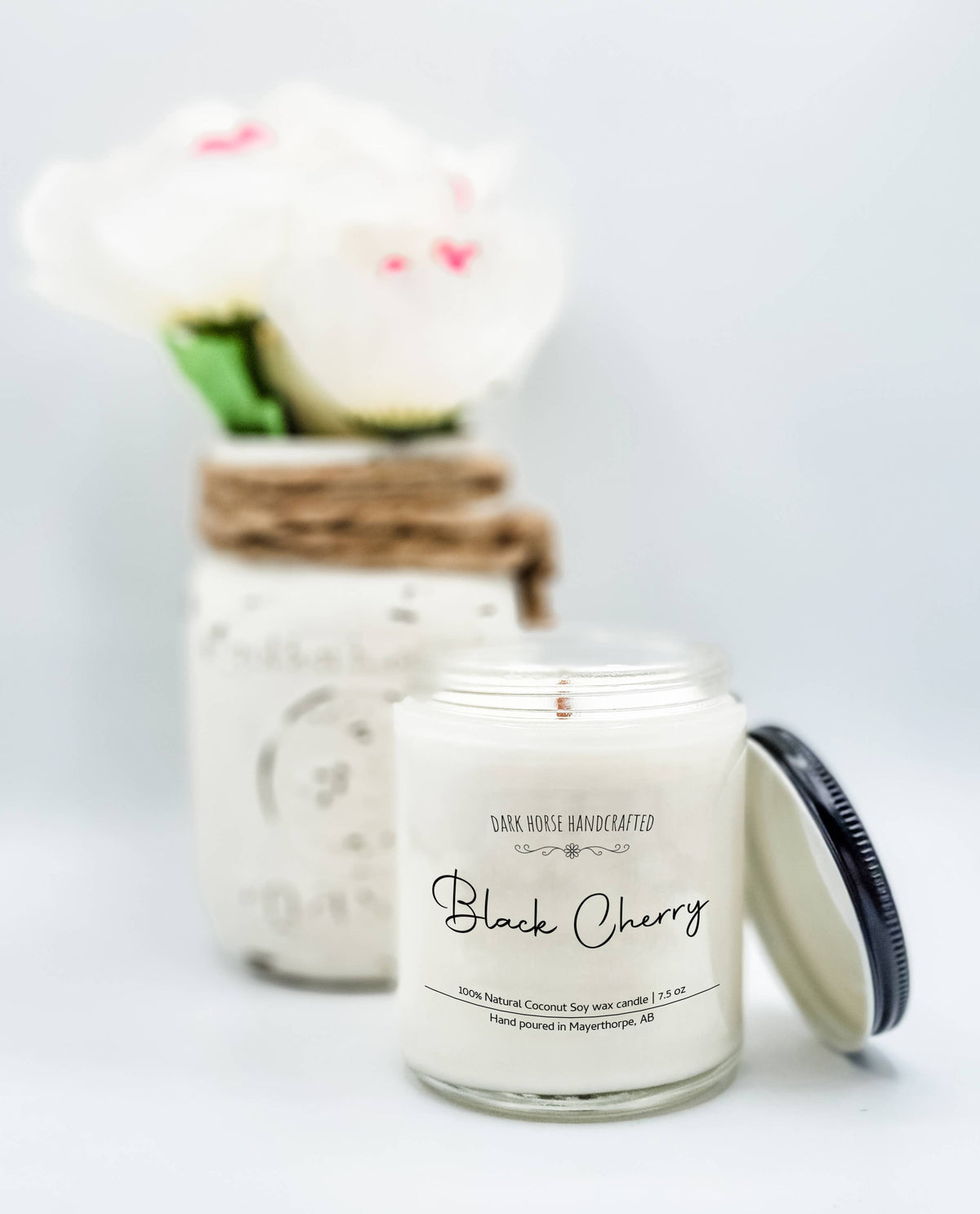 Black Cherry soy candle with black lid beside white blooms in a mason jar