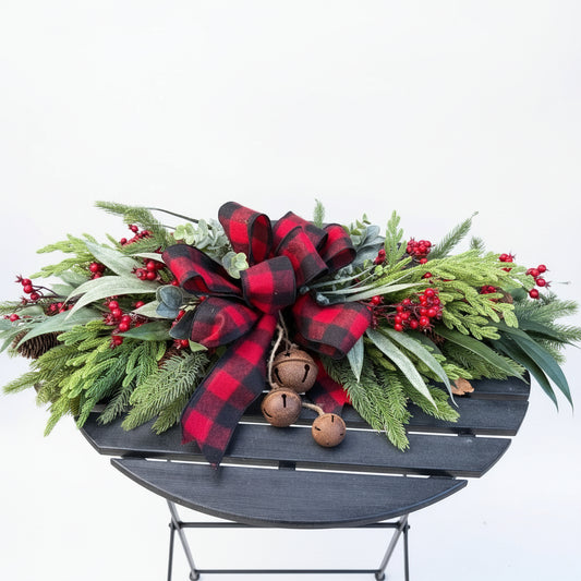 Decorative Christmas wreath with plaid ribbon and greenery on a chair.