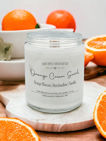 Orange Cream Swirl soy candle surrounded by fresh orange slices