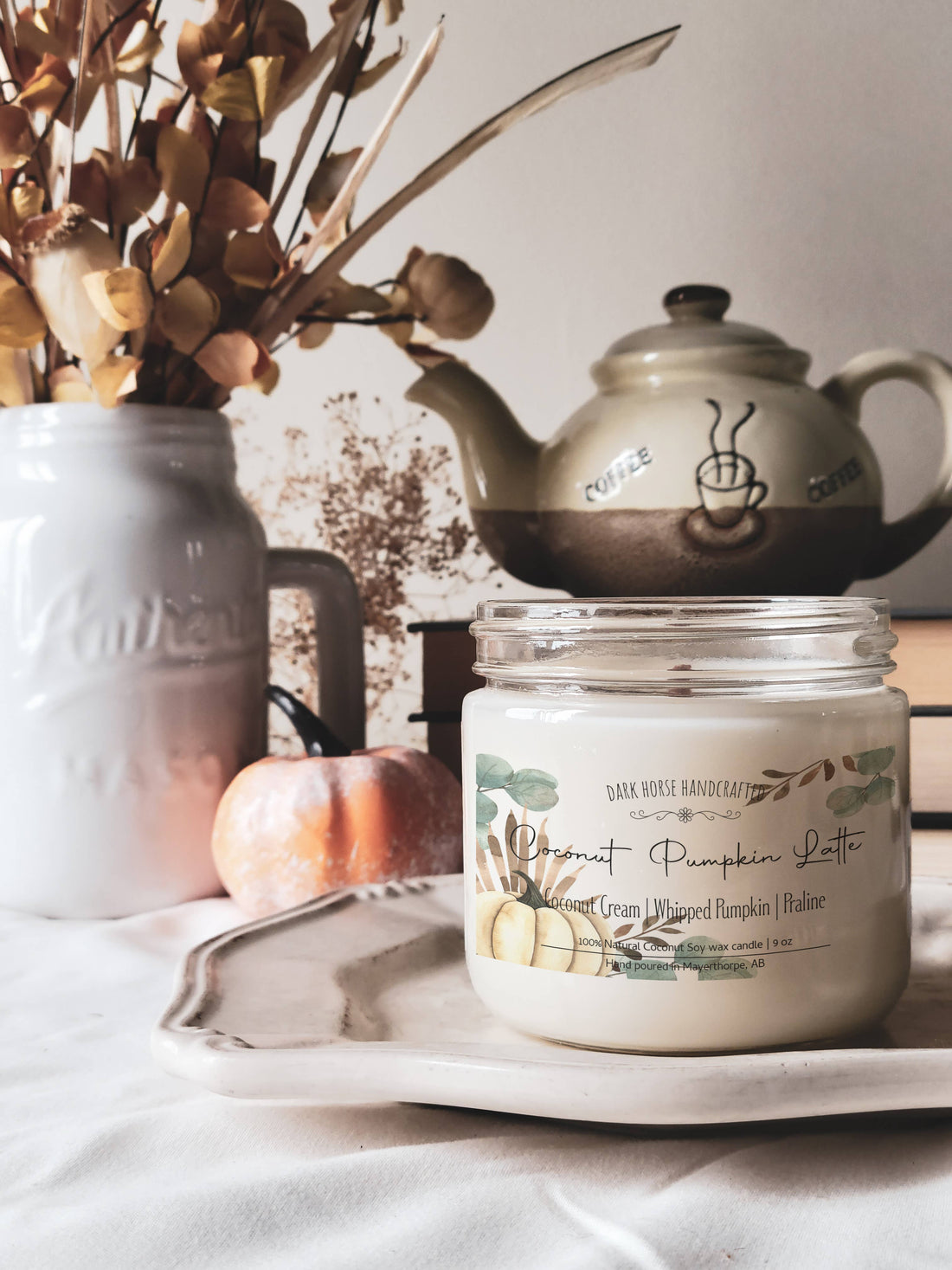 Pumpkin latte scented soy candle styled with a teapot and mini pumpkin