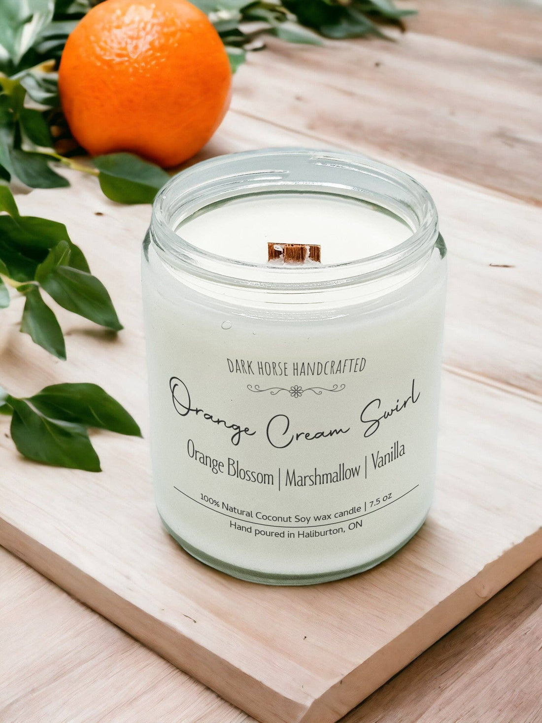 Orange Cream Swirl soy candle surrounded by fresh orange slices